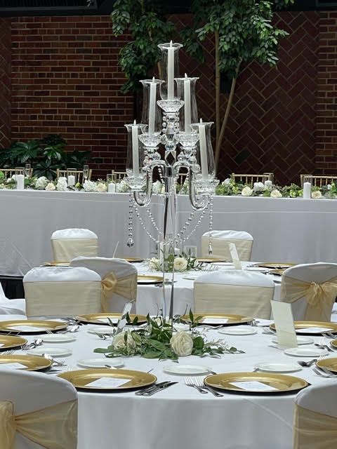 A table set for a wedding reception with a candelabra in the middle.
