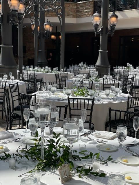 A table set for a wedding reception with lots of tables and chairs