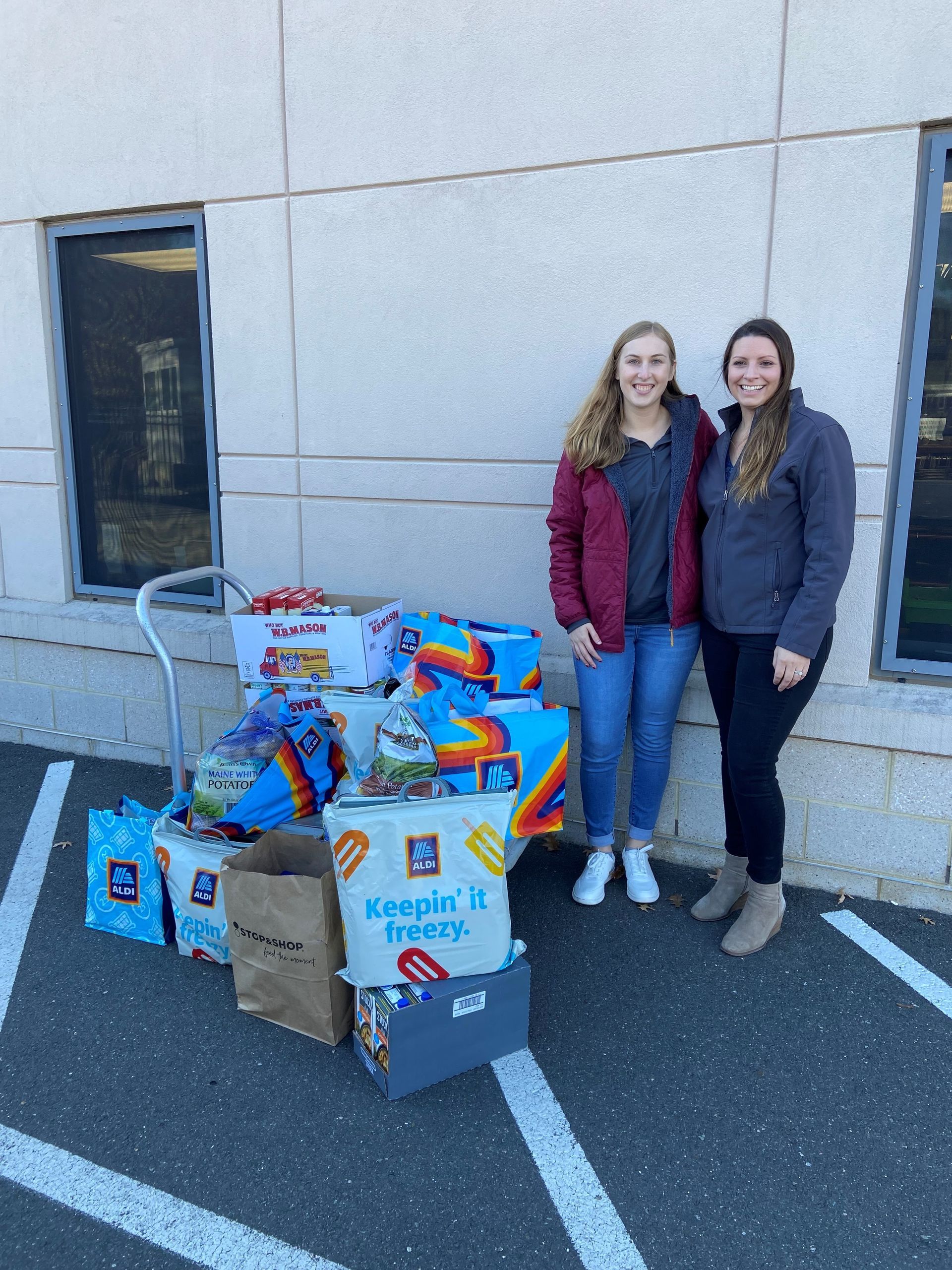 Mallory Beauregard and Chelsea Russell, MBK CPAs, stand with a portion of the food collected by MBK