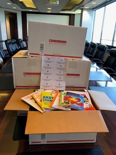 Five boxes of books are stacked on the boardroom table at MBK after being labeled and prepared to be delivered to organizations supporting children in our area.