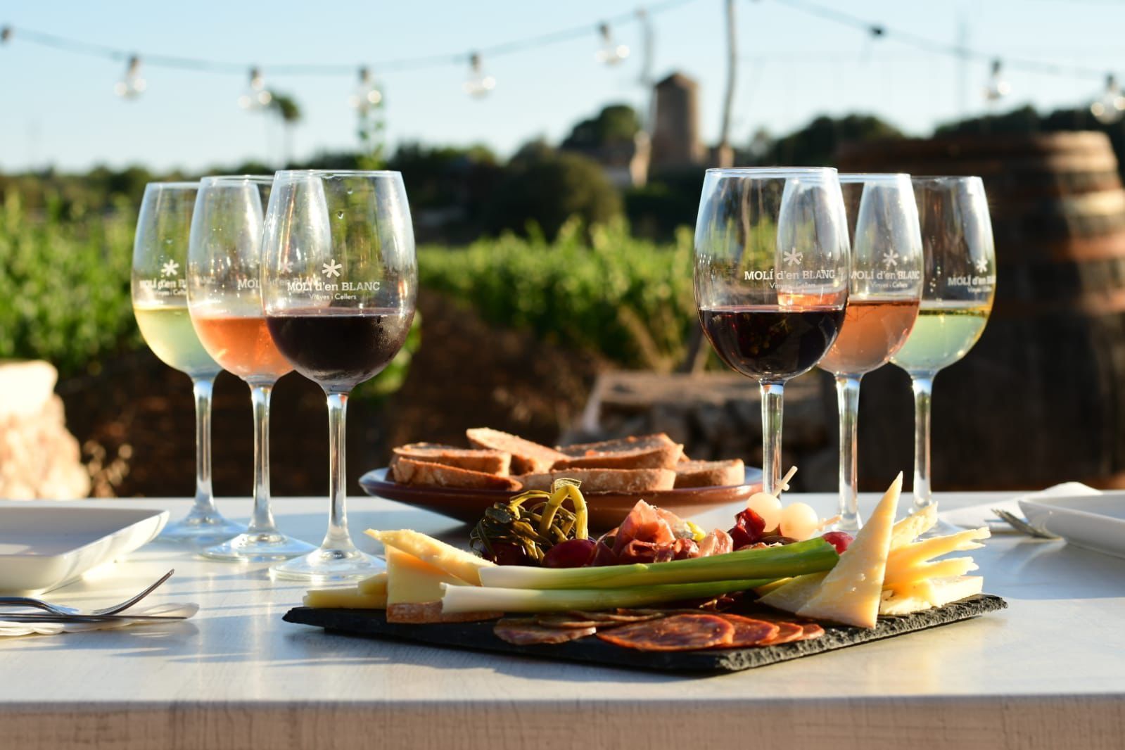 Una mesa con una bandeja de comida y copas de vino encima.