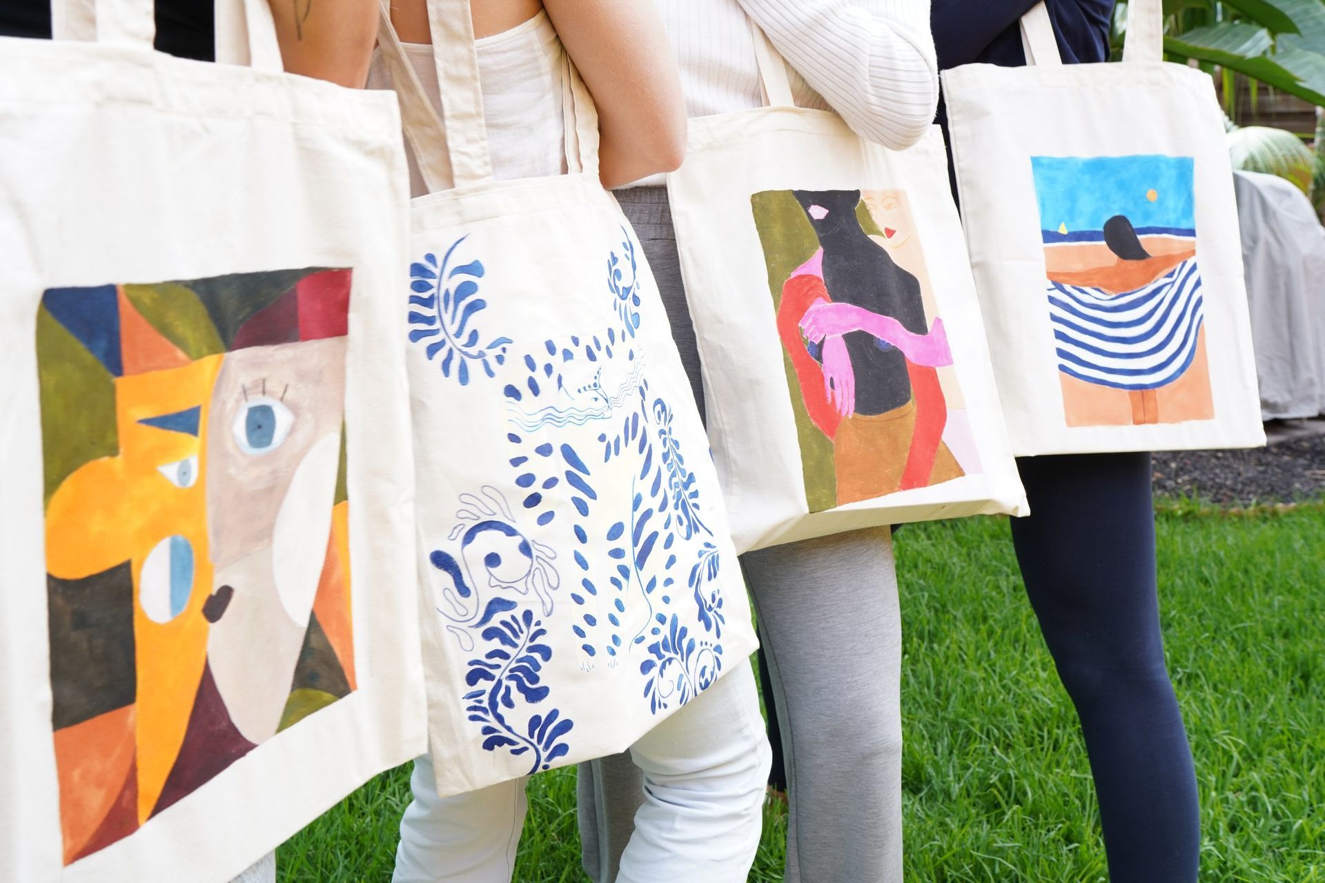 Un grupo de personas sosteniendo bolsas de mano con pinturas en ellas.