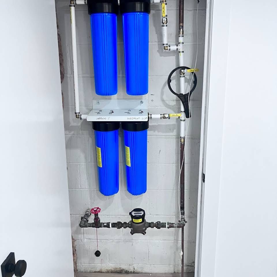 Two blue water filters are hanging on a white wall.
