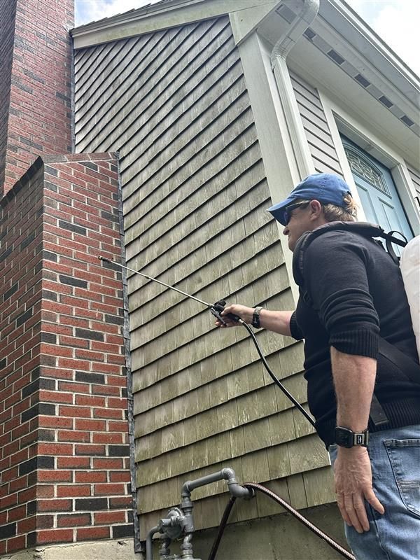 A man is spraying a house with a sprayer.