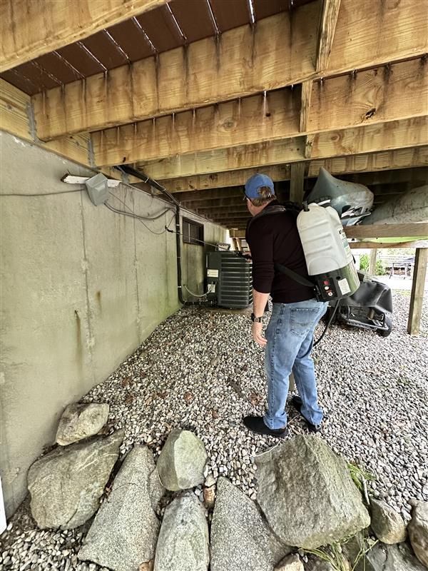 A man is spraying a house with a backpack.