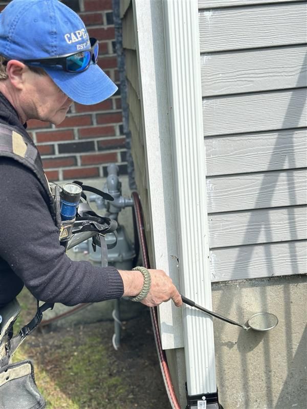 A man wearing a blue hat and sunglasses is working on a house.