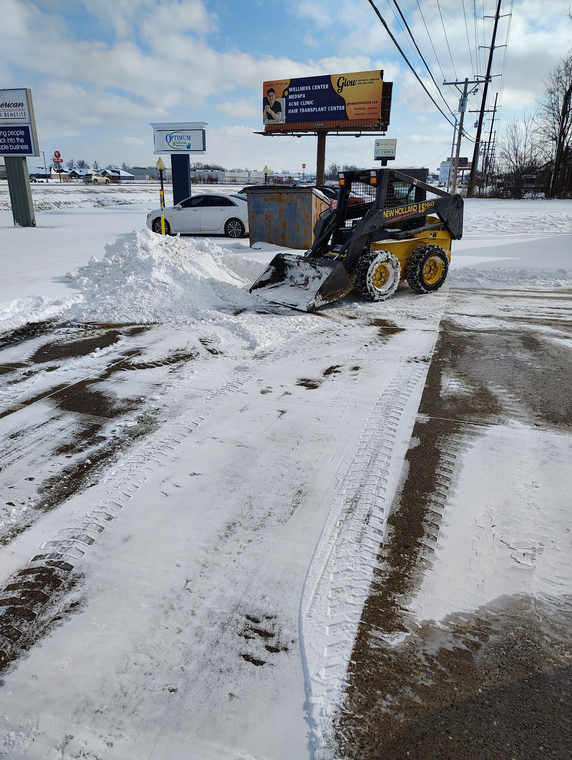A yellow cat bulldozer is loading trash into a dumpster.