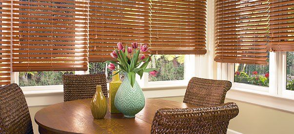 a dining room table with a vase of flowers on it and wooden blinds Love is Blinds Missouri (314) 808-3440.