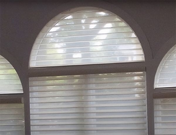 Love is Blinds St. Louis: There are three arched windows with white blinds on them.