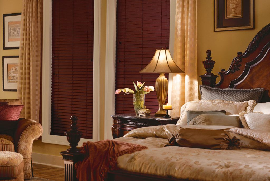 a bedroom with shutters on the windows, a large bed and a lamp Love is Blinds Missouri (314) 808-3440