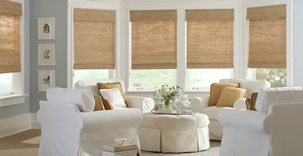 a living room filled with furniture and a round ottoman with woven roman shades on the windows Love is Blinds Missouri 