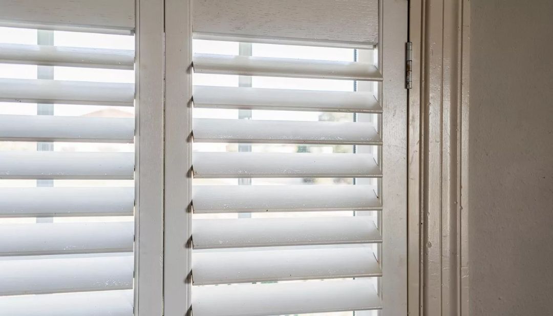 Close-up of plantation shutters in a Missouri home, showing realistic maintenance condition for wood and composite options by Love is Blinds.