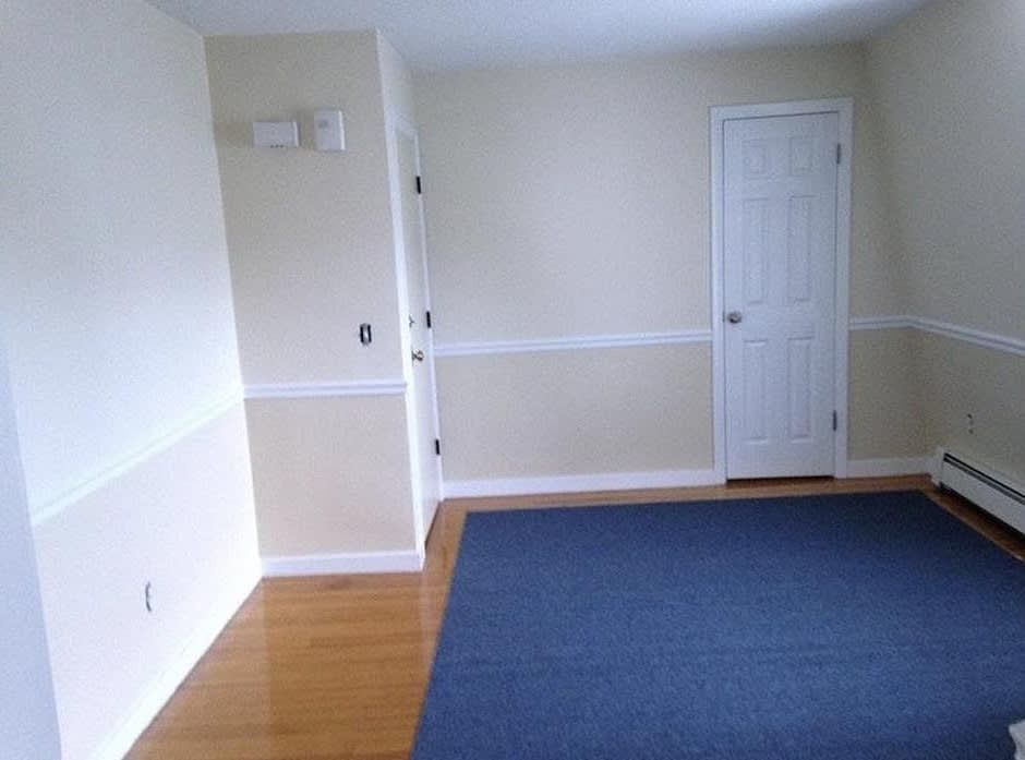 Empty room with blue carpet, cream walls, white trim, and a closed white door.