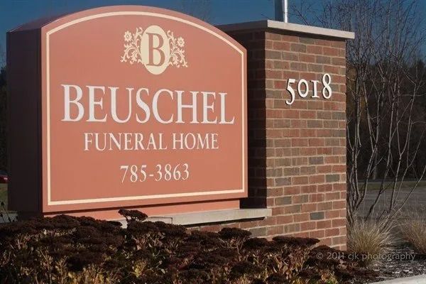 Sign for Beuschel Funeral Home, peach background, brick pillar with address 5018.