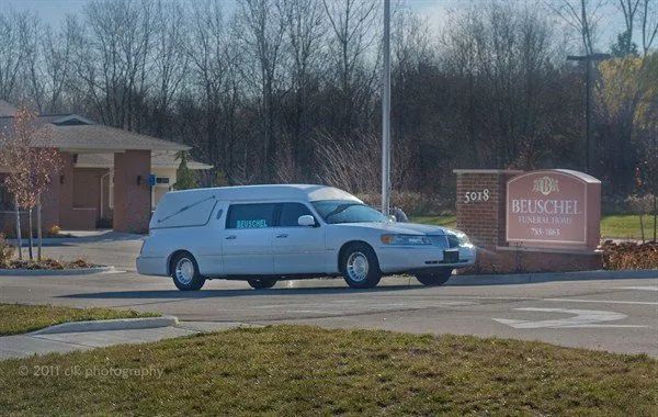 Hearse in front of a building with a sign that reads 