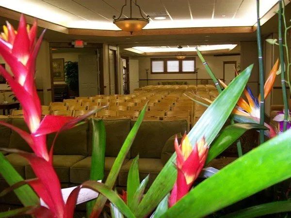 Red and yellow flowers in foreground, rows of chairs and a few sofas in a conference room.