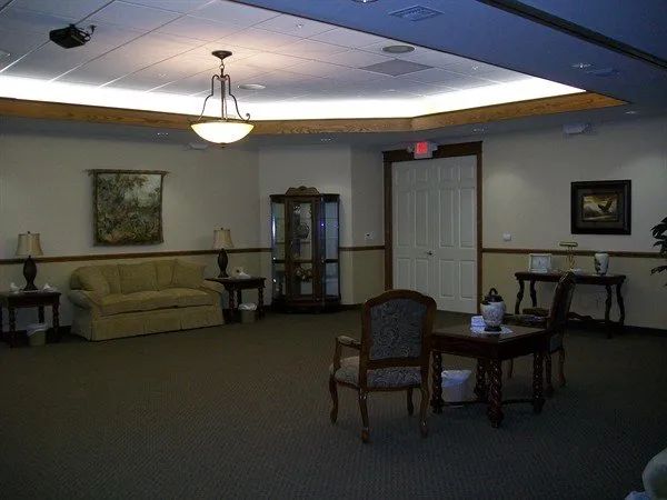 Waiting room with sofa, chairs, tables, and a display cabinet.