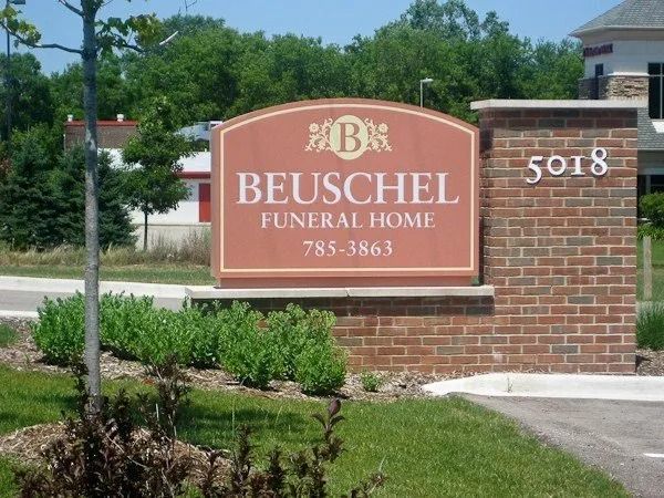 Sign for Beuschel Funeral Home, with building number 5018. Red sign on a brick base.