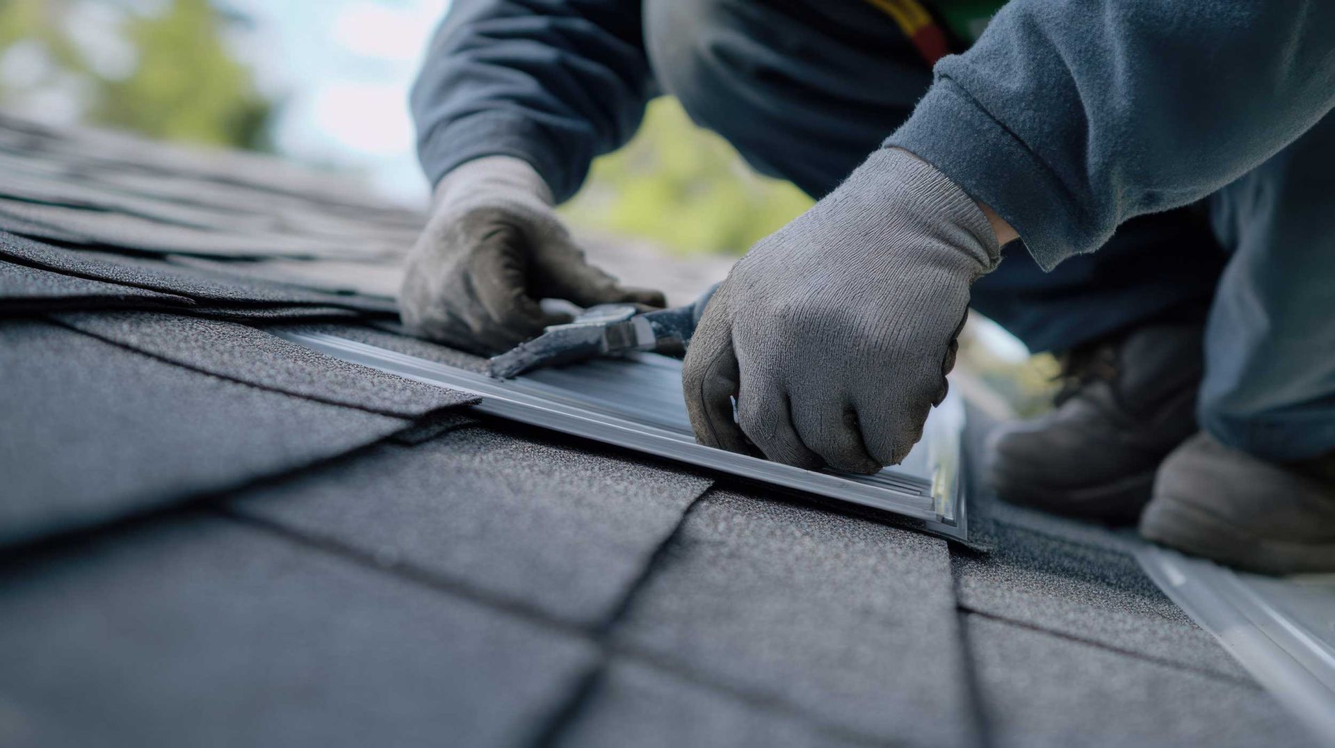 Close-up of a roofer installing metal valley flashing during roofing services on a shingle roof.