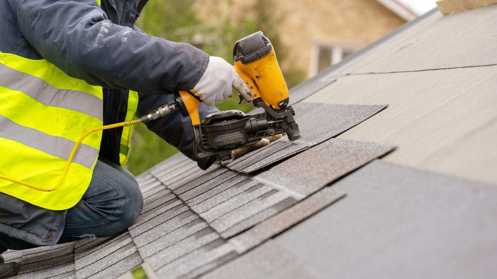 A worker securing new shingles on a residential roof, showcasing reliable home roofing services. A worker securing new shingles on a residential roof, showcasing reliable home roofing services.