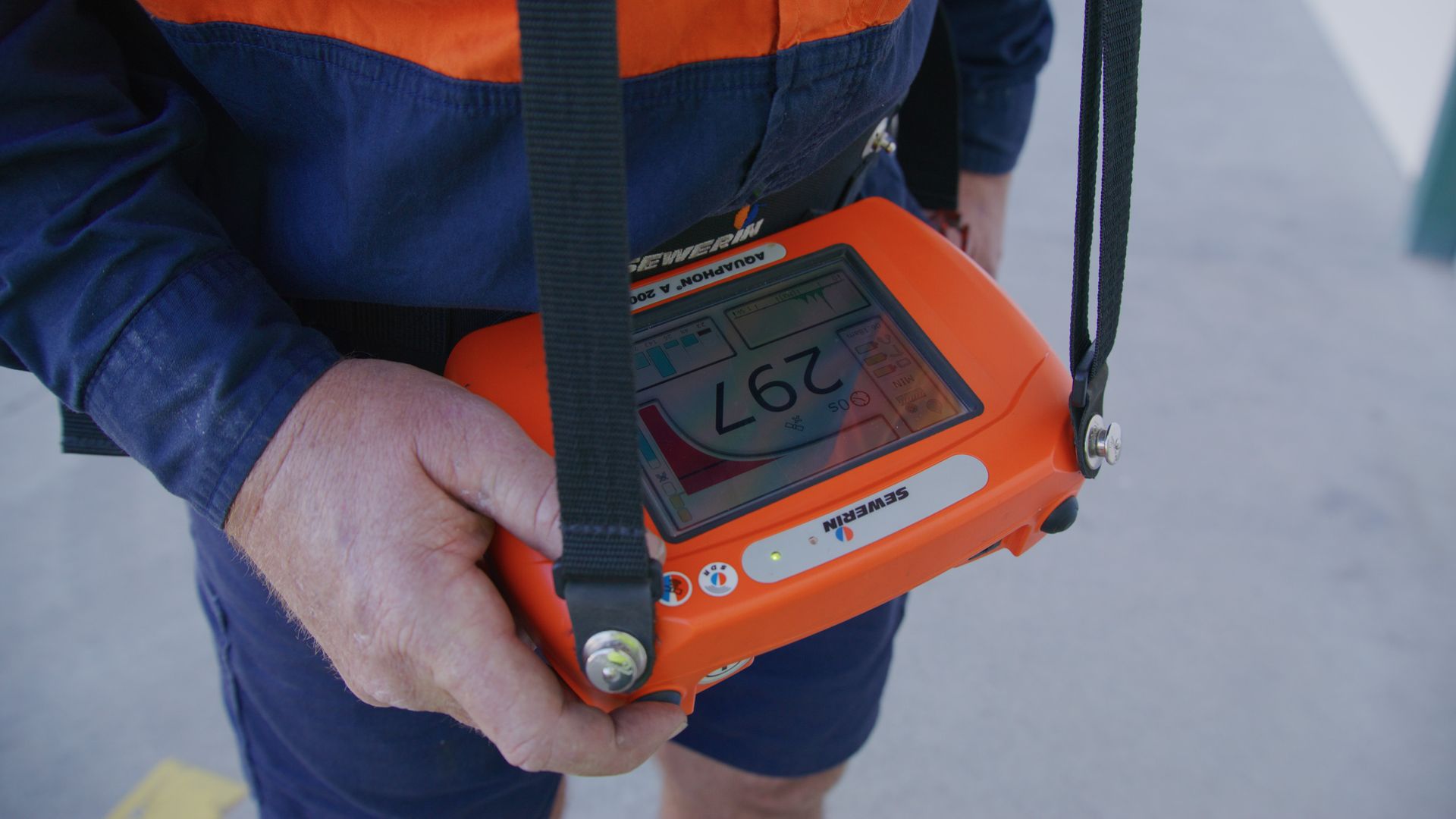 Person in Workwear Holds an Orange Gas Detector — Commercial Leak Detection in Mudgeeraba, QLD