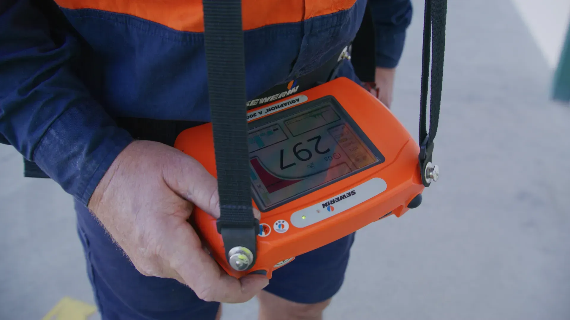 Person holding an orange gas detector, displaying 