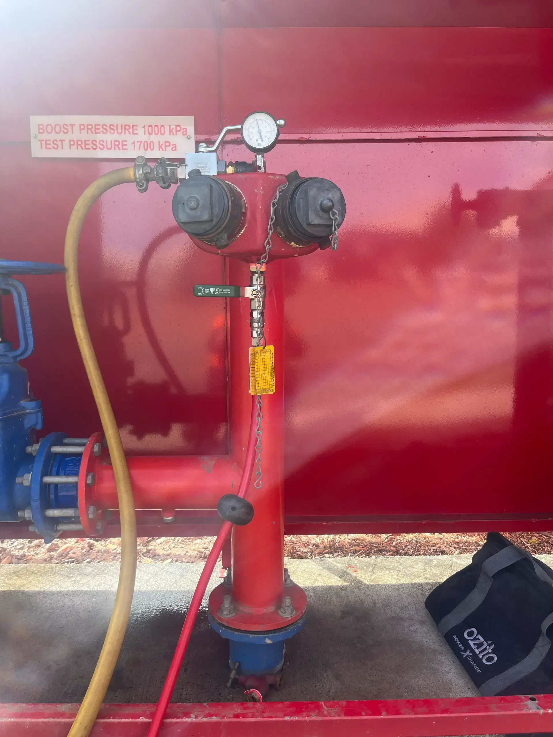 Red fire hydrant with two outlets, a gauge, and attached hoses.  — Commercial Leak Detection