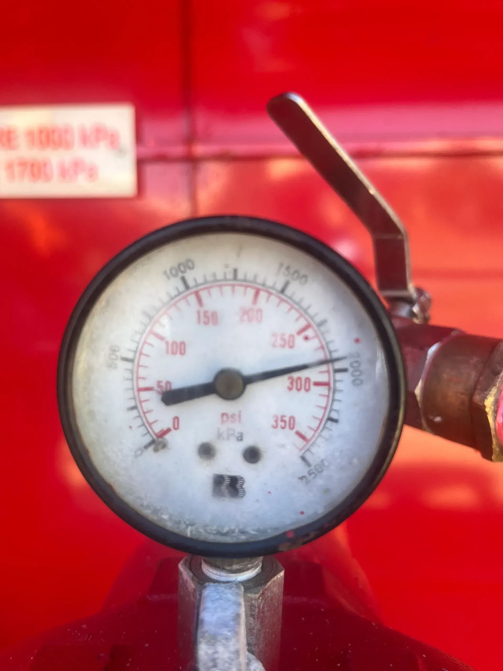 Pressure gauge with a needle pointing to about 280, mounted on red equipment.  — Commercial Leak Detection 