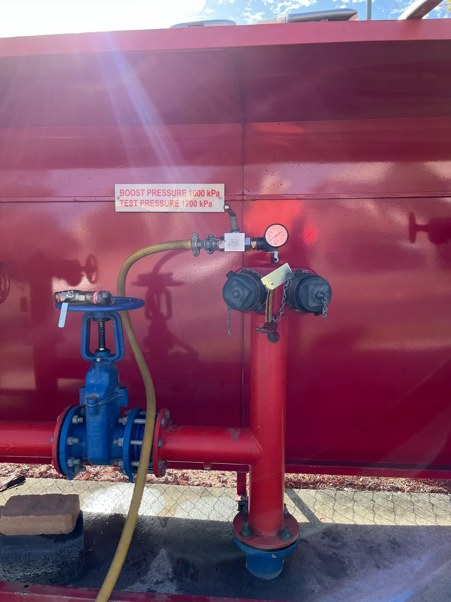 Red tank with blue valve, connected pipes, and gauges.  A yellow hose is attached to the system.  — Commercial Leak Detection