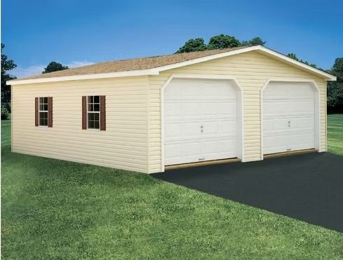 Tan beige two-car garage with white doors, brown roof, and two windows on a grassy lot.