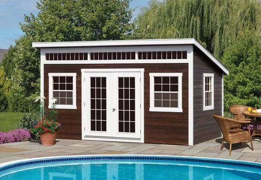 Brown backyard pool house with white double doors and windows beside a swimming pool