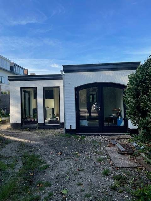 Een wit huis met zwarte ramen en een blauwe lucht op de achtergrond