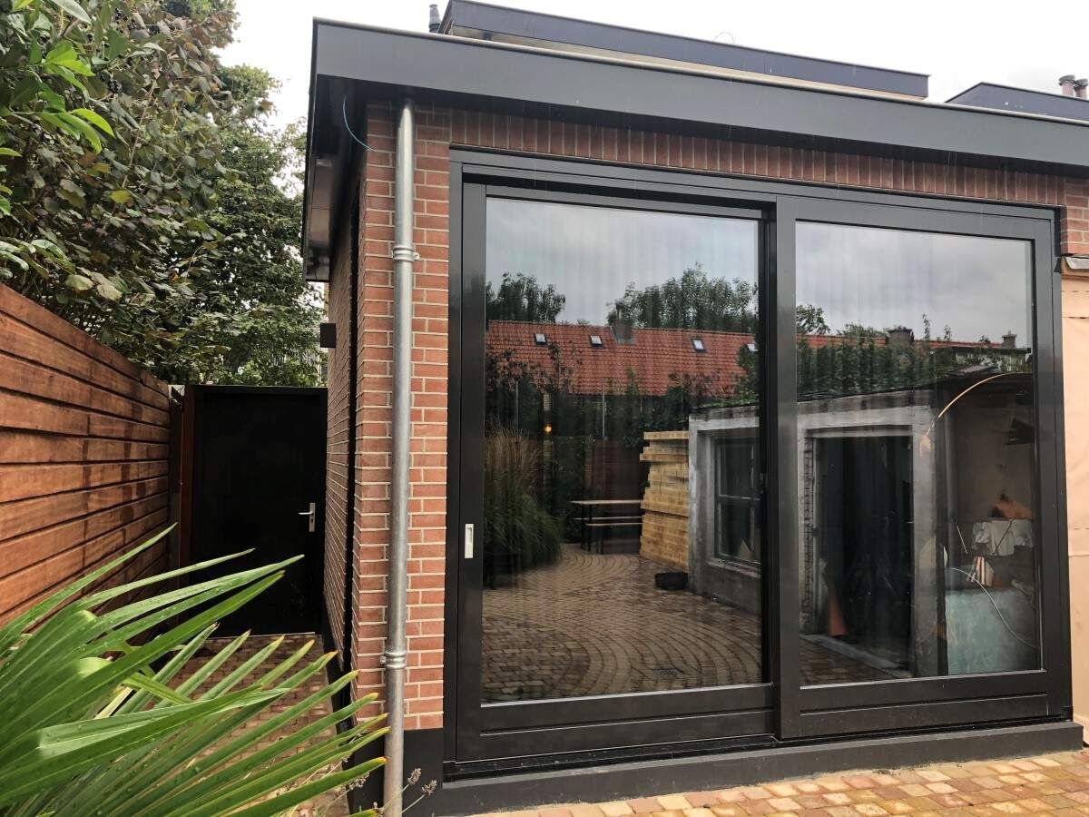 Een bakstenen gebouw met een groot raam en glazen schuifdeuren.