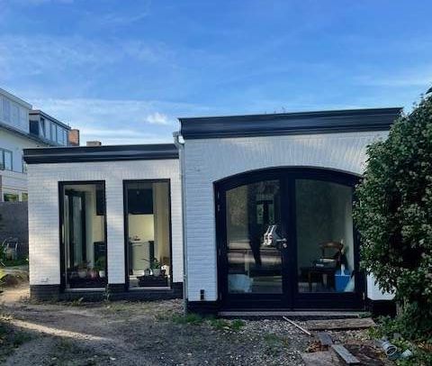 Een wit bakstenen huis met zwarte afwerking en veel ramen