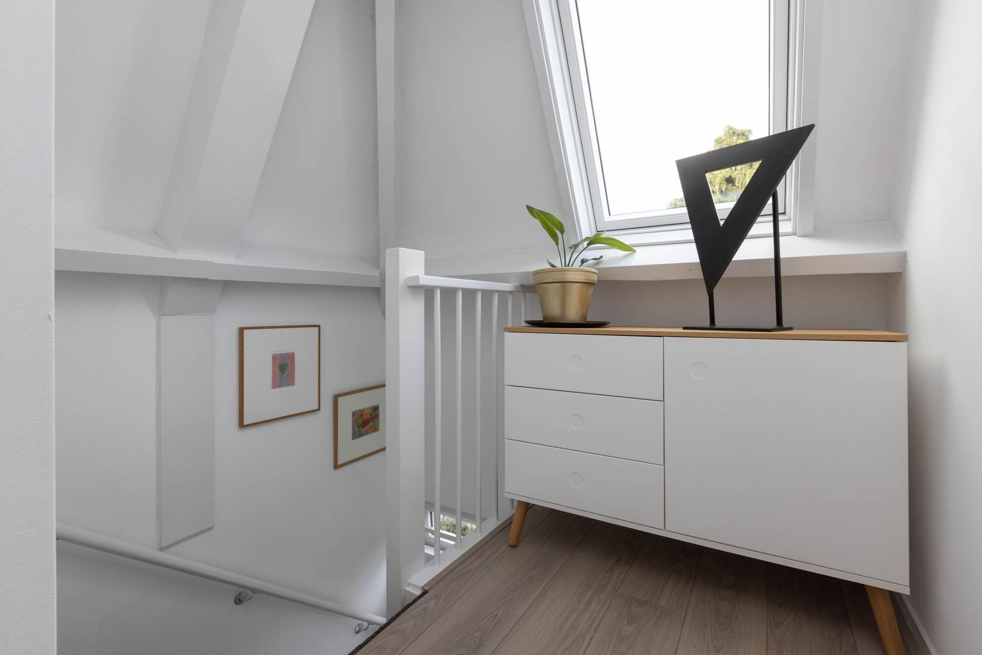 Een kleine kamer met een ladekast en een raam.