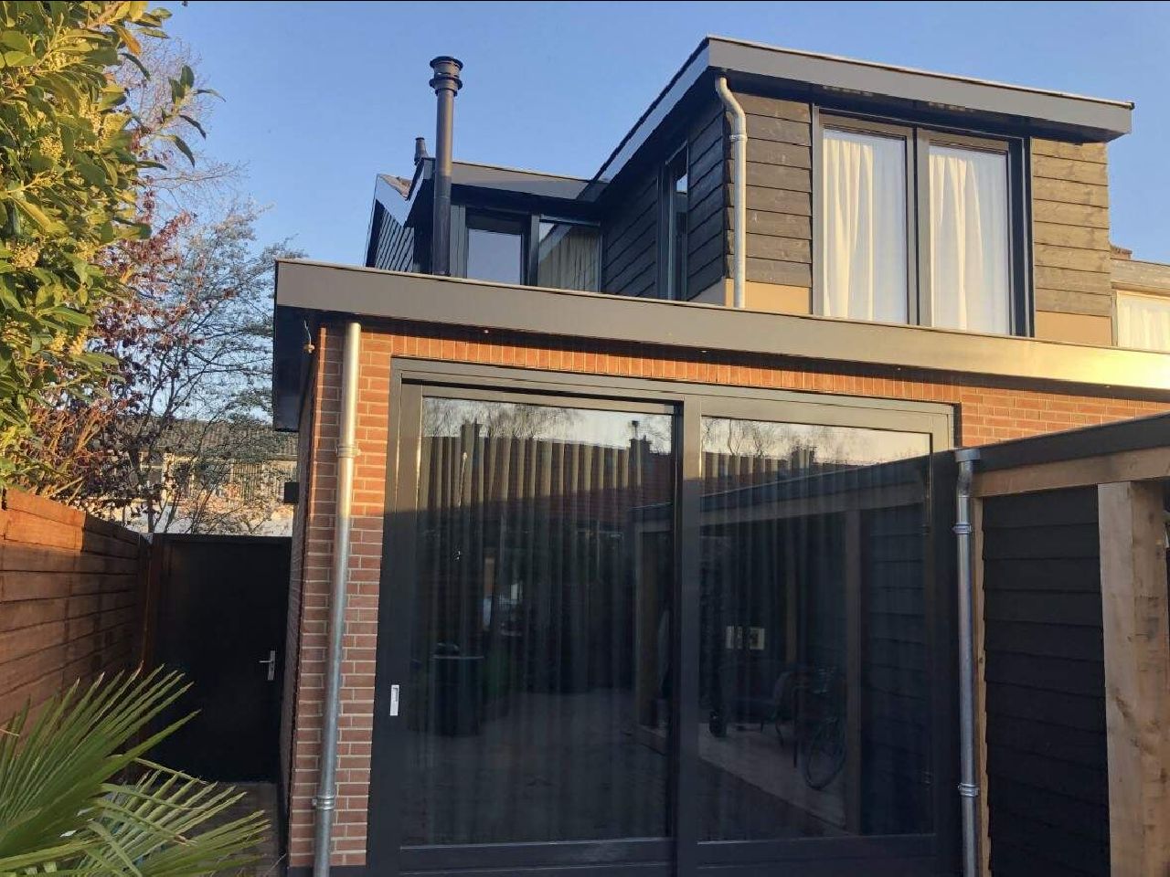 Een huis met veel ramen en een schoorsteen op het dak