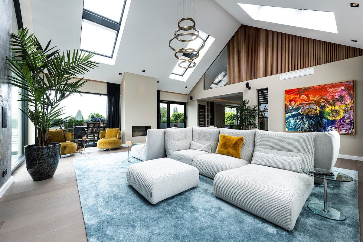 Een woonkamer met een bank, stoelen en een schilderij aan de muur.