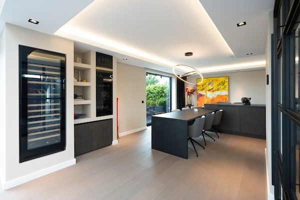 Een eetkamer met een tafel en stoelen en een wijnkoeler