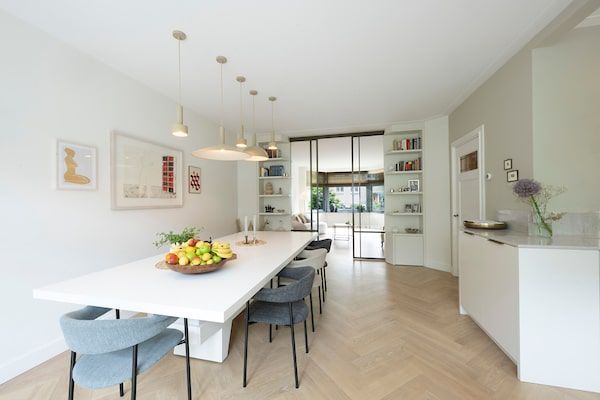 Een eetkamer met een lange witte tafel en stoelen