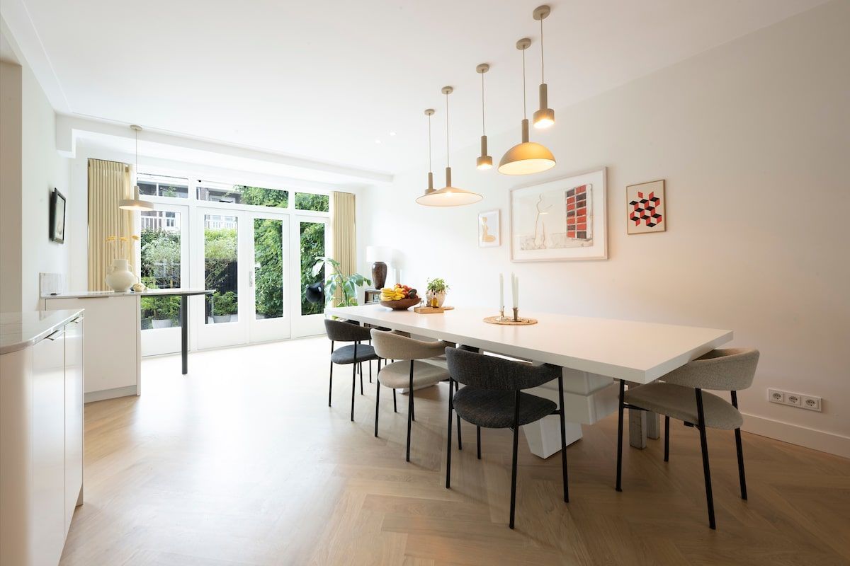 Een eetkamer met een lange witte tafel en stoelen.