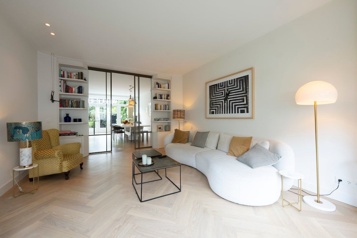 Een woonkamer met een bank, stoel, salontafel en lamp.