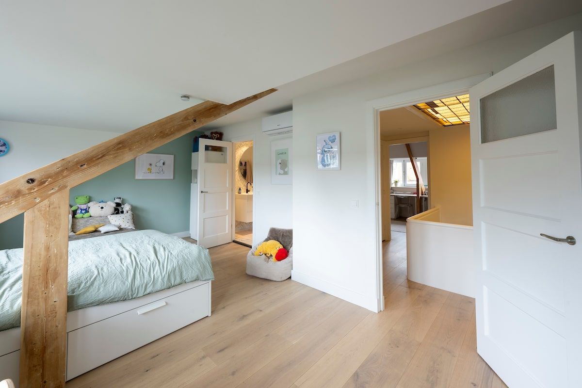 Een slaapkamer met een bed en een houten balk in het plafond.