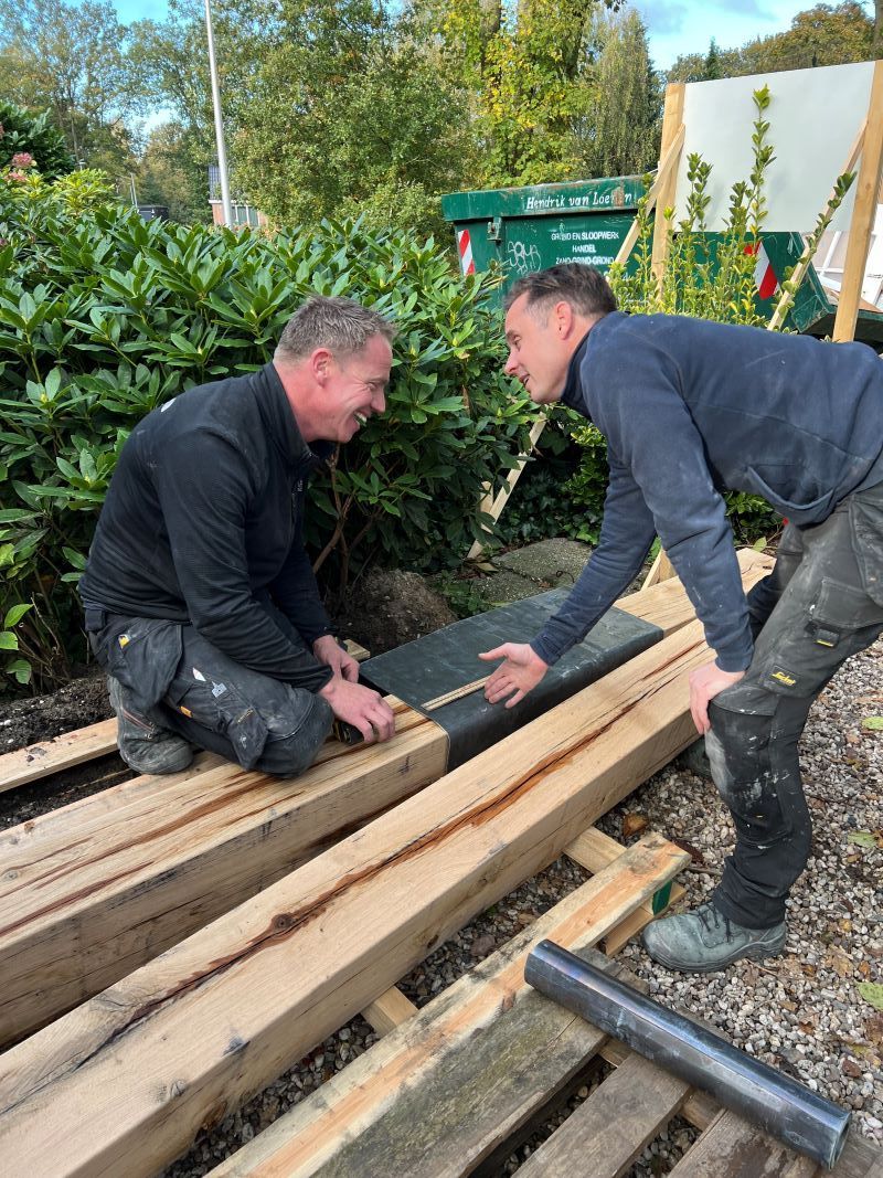 Twee timmermannen werken met een paar houten palen.