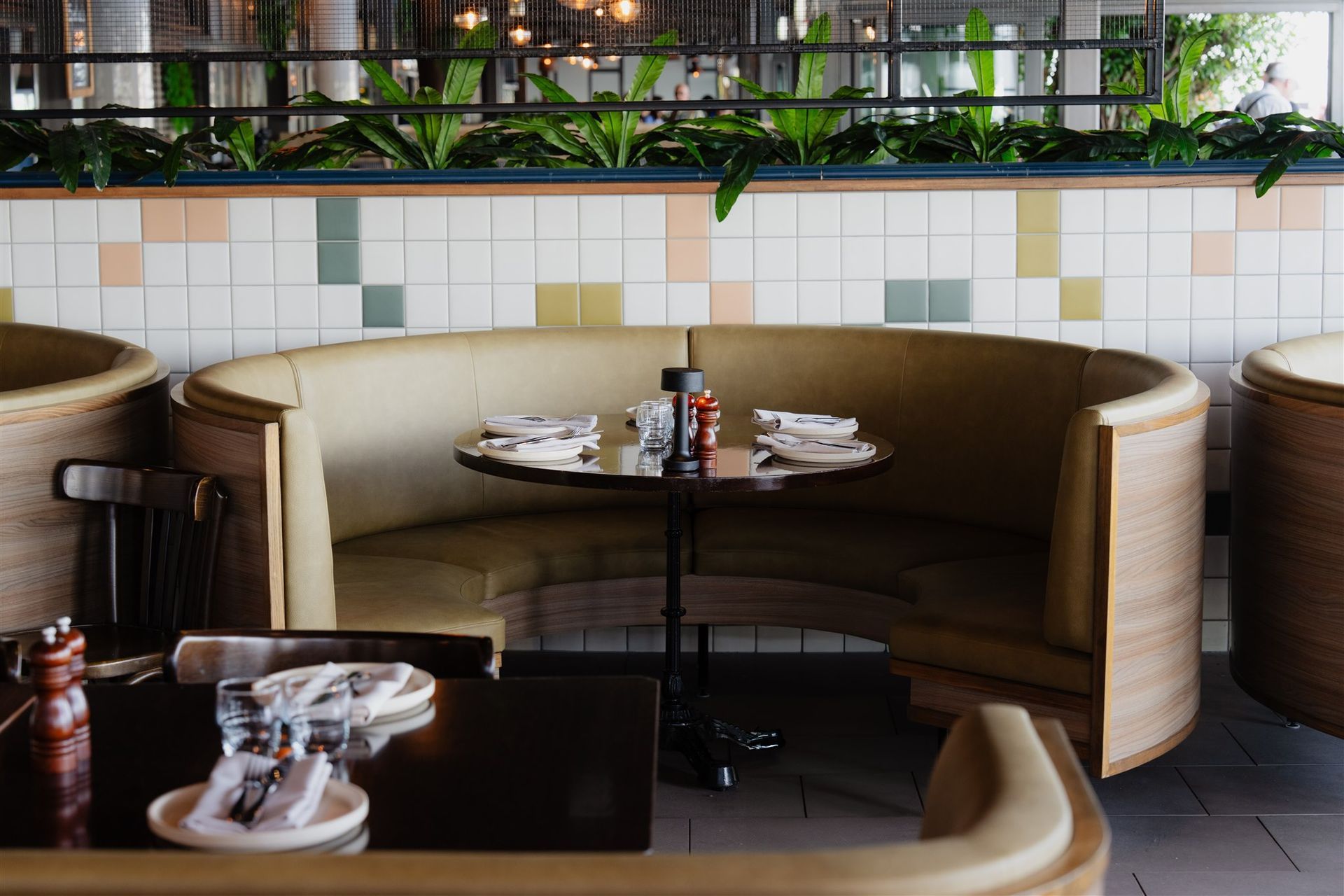 Curved booth seating with timber joinery and tiled wall backdrop
