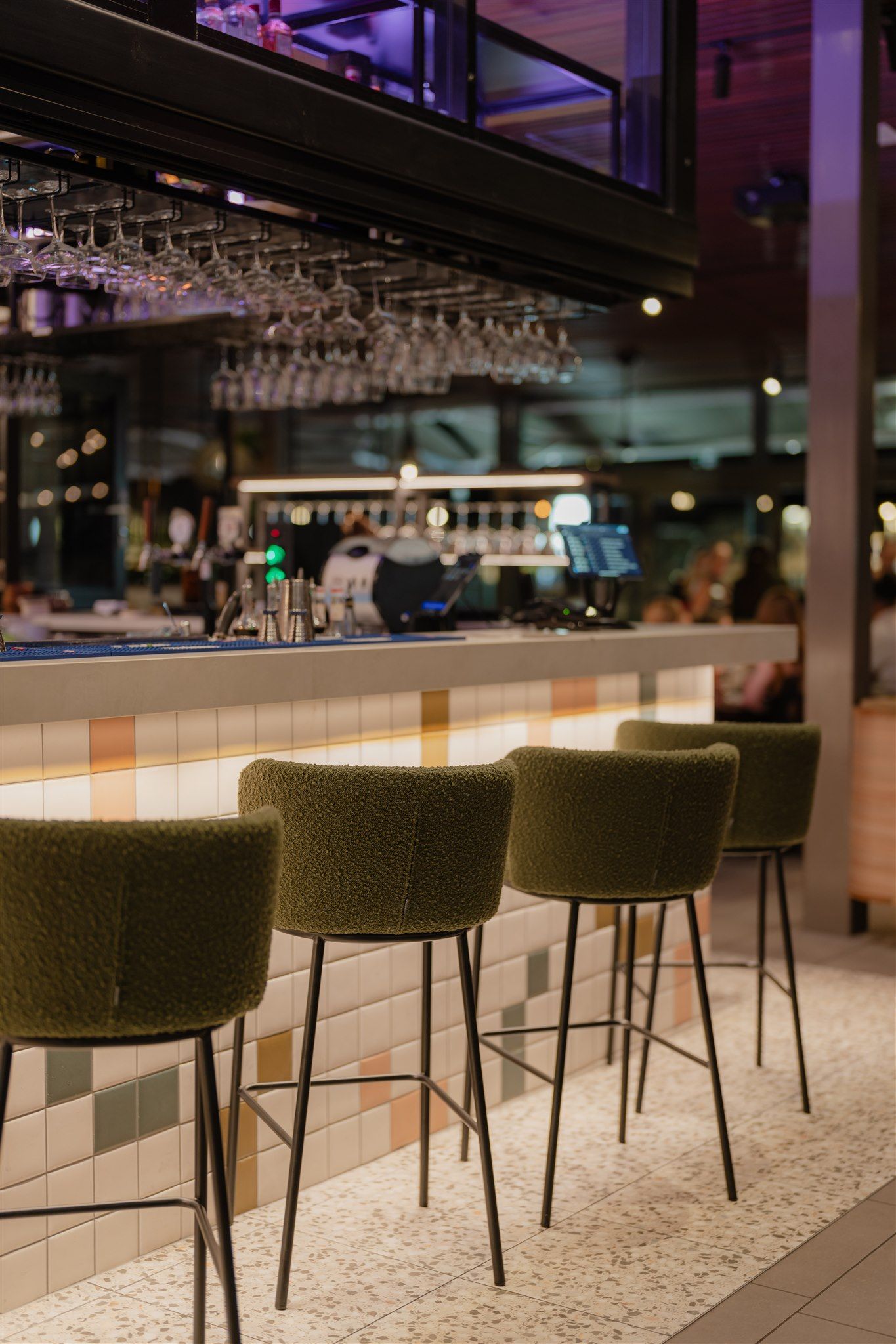 Bar seating with tiled bar front, upholstered stools and integrated under-bench lighting