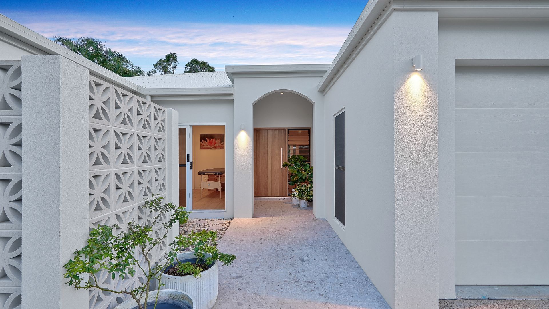 Entry courtyard with breeze block wall, arched doorway and planting