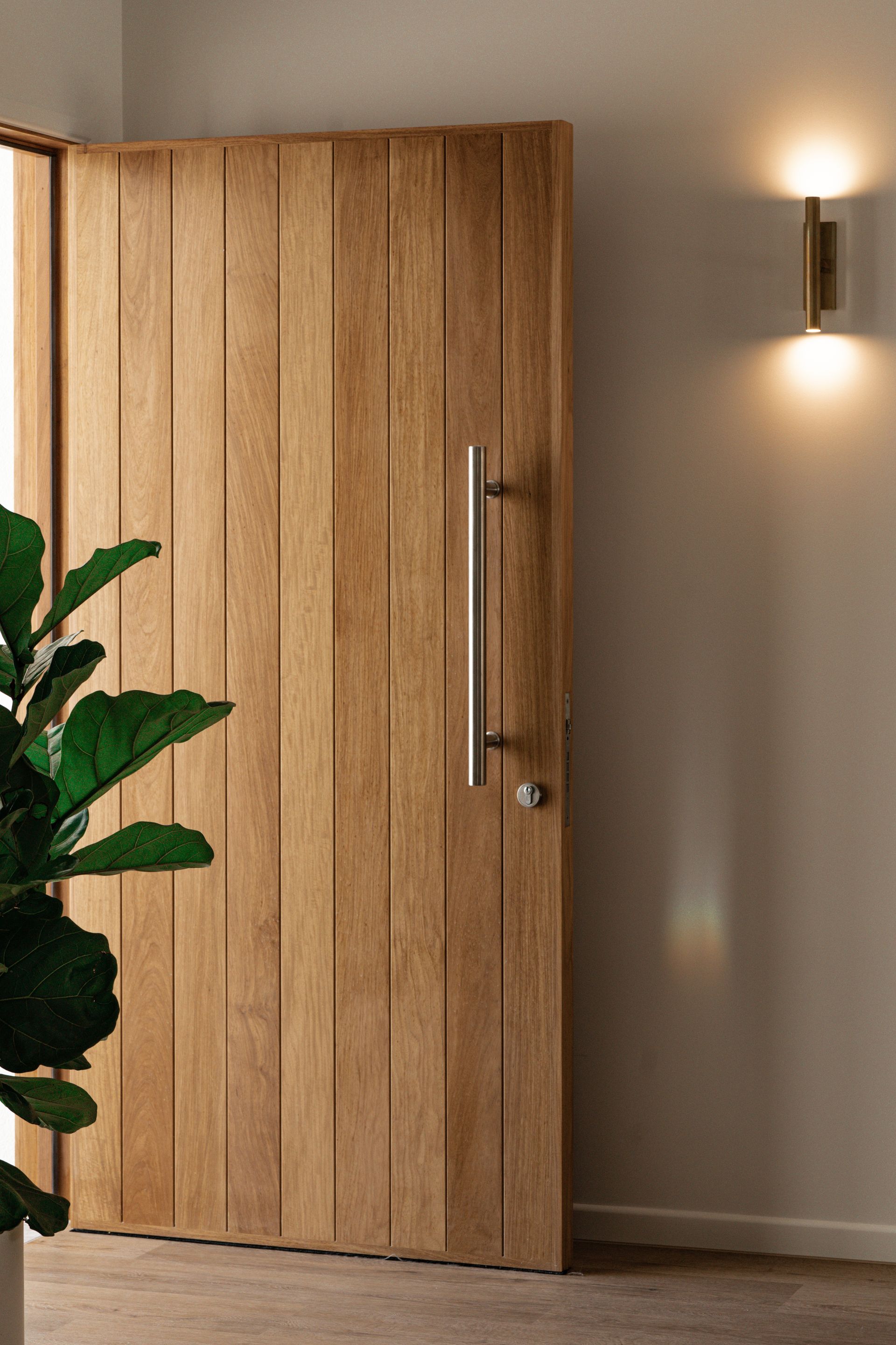 Timber front door with vertical panelling and wall lighting detail
