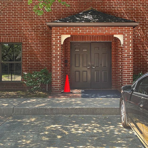 A brick house with cars parked in front of it