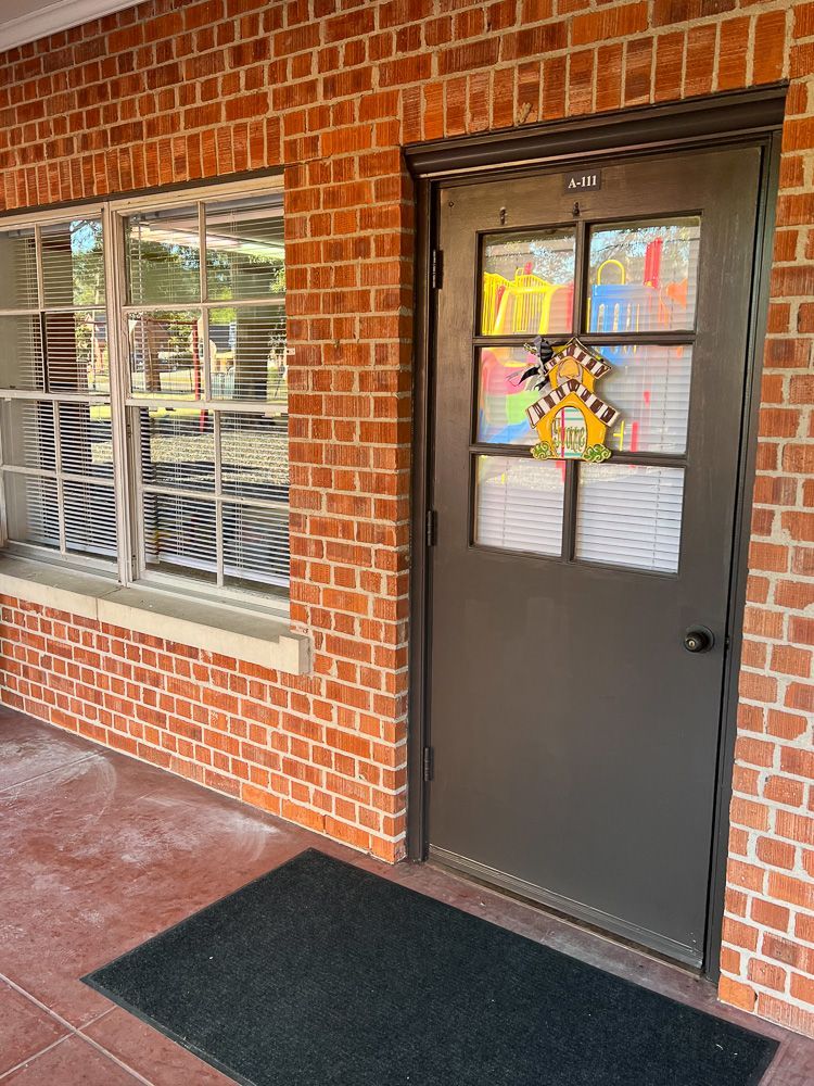 A brick building with a black door and a black mat in front of it.