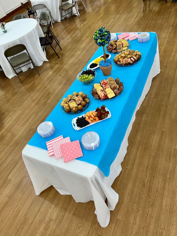 A long table with a blue tablecloth and plates of food on it.